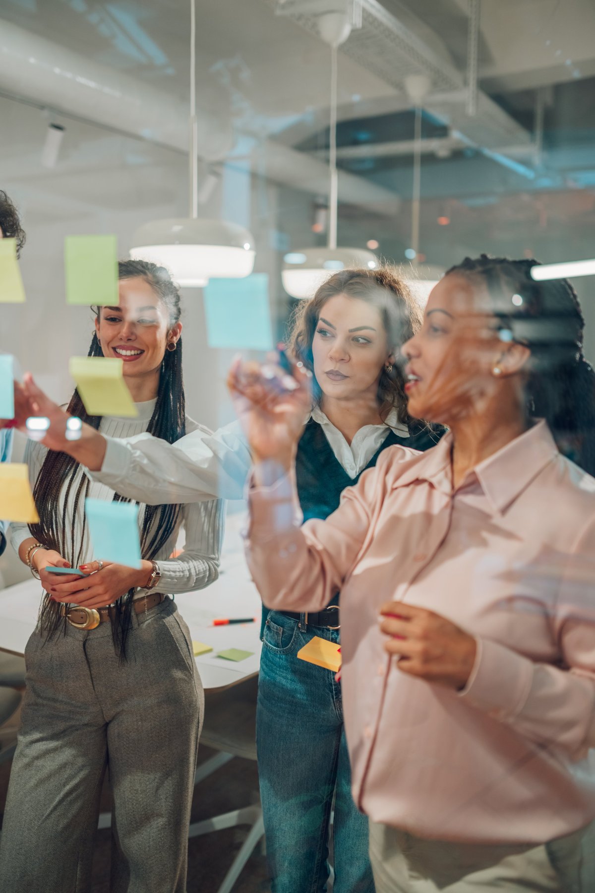 Equipo profesional colaborando en una sesión de desarrollo de estrategia con notas adhesivas en una pared de vidrio